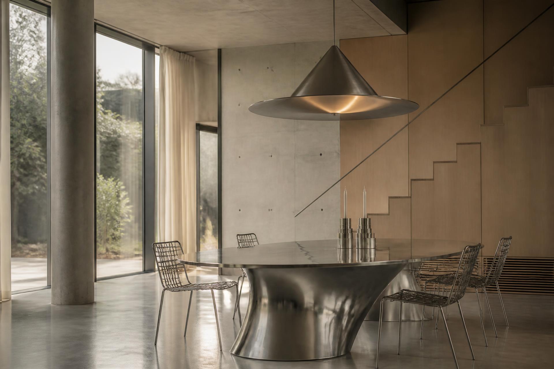 Luxury modern interior with a sculptural metal dining table and designer pendant lighting